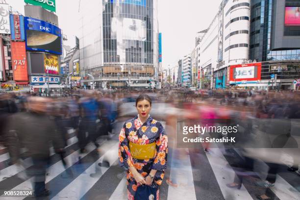 britse vrouw in kimono staande in drukke shibuya kruising - lange sluitertijd stockfoto's en -beelden