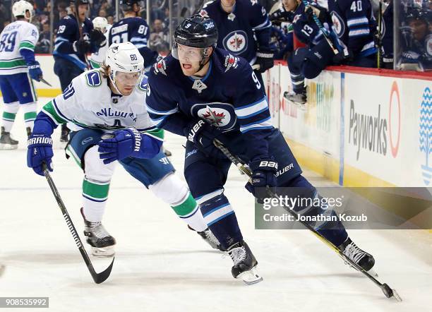 Andrew Copp of the Winnipeg Jets plays the puck away from Markus Granlund of the Vancouver Canucks during first period action at the Bell MTS Place...