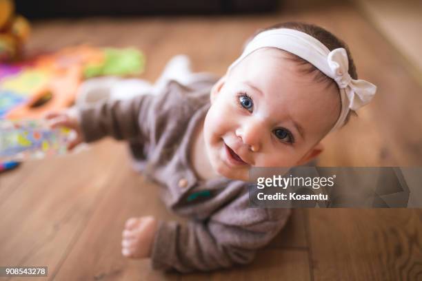 cute baby girl crawling in living room - baby girls stock pictures, royalty-free photos & images