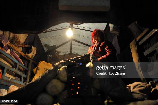 Woman sits near a coal stove selling cabbages as recent temperatures dropped to as low as -35 C on January 22, 2018 in Harbin, China.