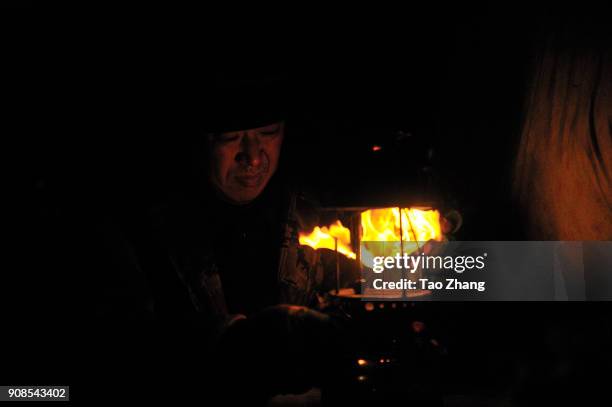 Man lights a kerosene burner for heat as recent temperatures dropped to as low as -35 C on January 22, 2018 in Harbin, China.