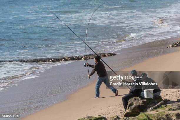 Men enjoy fishing by the sea on a sunny afternoon in Tamariz Beach on January 20, 2018 in Estoril, Portugal. Estoril is an all year round favorite...