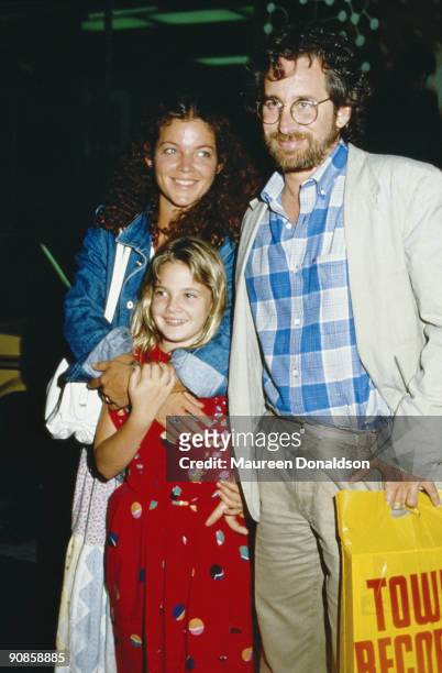 American film director Steven Spielberg out shopping with his wife Amy Irving and child actress Drew Barrymore, circa 1985. Barrymore starred in...