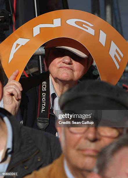 An elderly woman uses a sign that reads: "Angie," in reference to Chancellor and German Christian Democratic Union Chairwoman Angela Merkel, to shade...