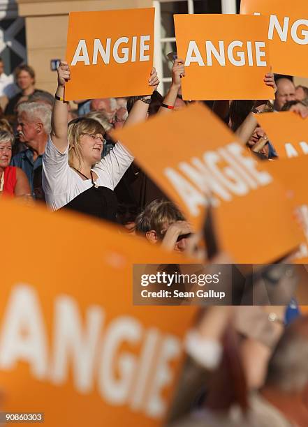 People hold up signs that read: "Angie" in reference to Chancellor and German Christian Democratic Union Chairwoman Angela Merkel at a CDU election...