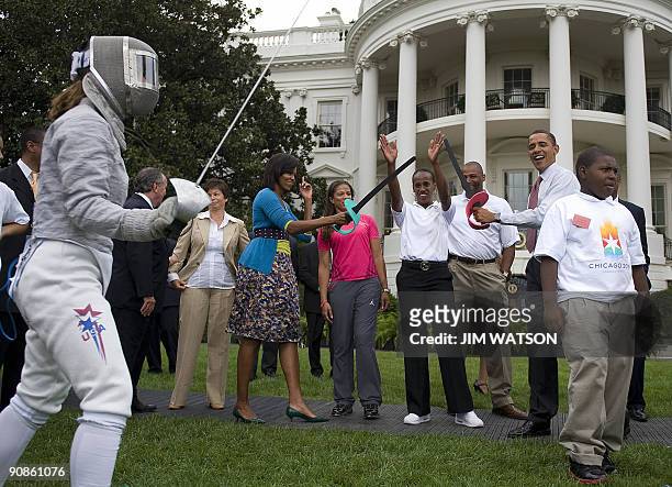 President Barack Obama pretends to fence with First Lady Michelle Obama during an event on Olympics, Paralympics and youth sport on the South Lawn of...