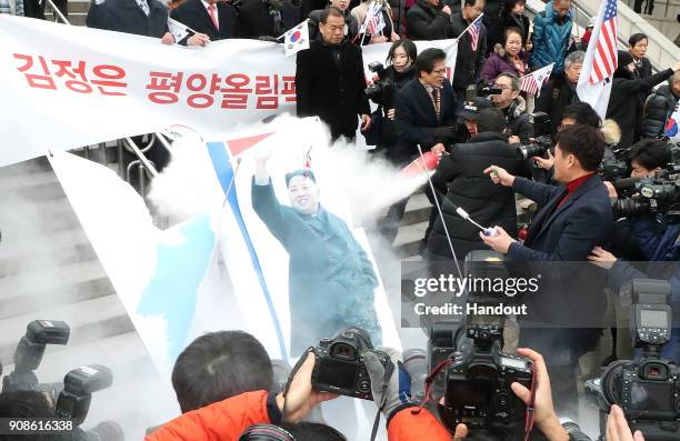 Anti-North Korea activists burn a portrait of North Korean leader Kim Jong-Un during a rally as a North Korean delegation arrives at the station on...