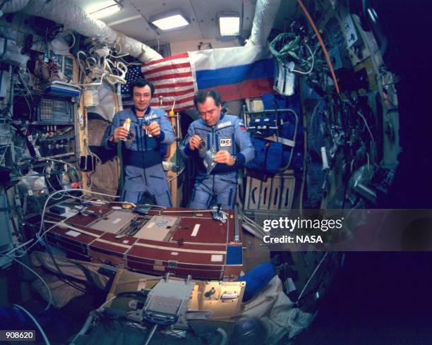 Mir 18 crew Vladimir Dezhurov, left, and Gennady Strekalov enjoy a meal inside the Mir space station. On March 12 it has been reported that the aging...