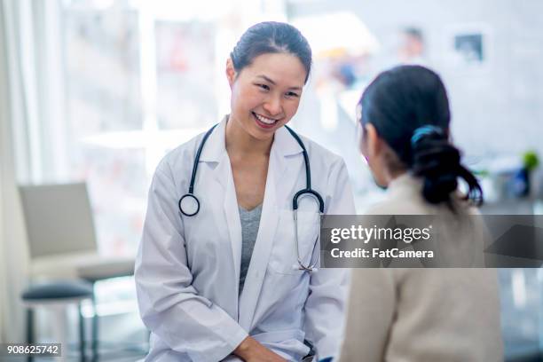 at the doctor's office - female doctor stock pictures, royalty-free photos & images