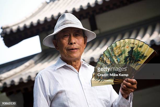 senior man holding fan and smiling with motion blur - folding fan stock pictures, royalty-free photos & images