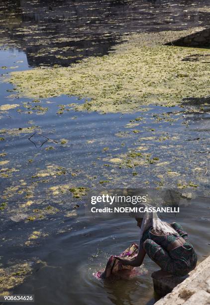 This picture taken on January 18, 2018 shows an Indian woman washing clothes in polluted water of a sacred water tank at Ekling Ji Kund, about 22km...