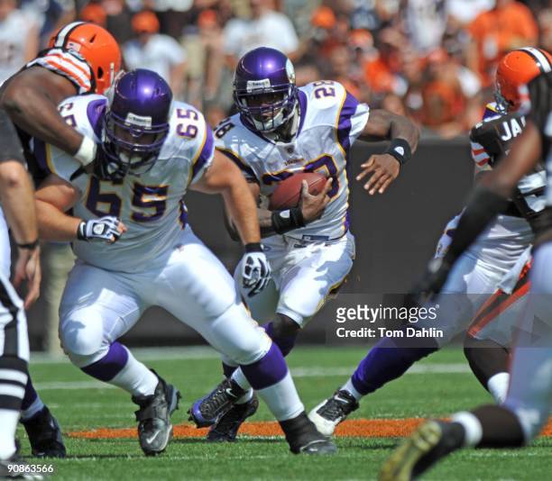 Adrian Peterson of the Minnesota Vikings carries the ball behind a block by teammate John Sullivan during an NFL game against the Cleveland Browns,...