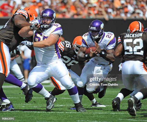 Adrian Peterson of the Minnesota Vikings carries the ball behind a block by teammate John Sullivan during an NFL game against the Cleveland Browns,...