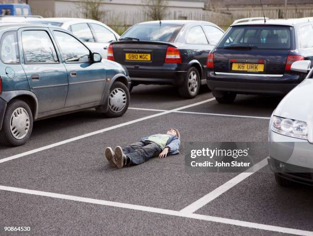 boy lying down in parking lot - boy lying down stock pictures, royalty-free photos & images