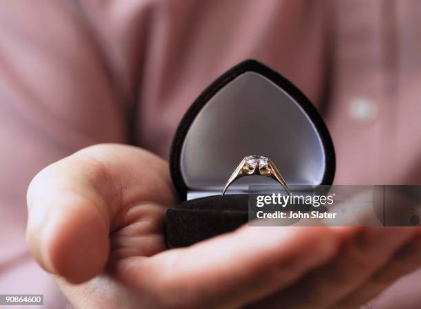 close-up of hand holding engagement ring - engagement imagens e fotografias de stock