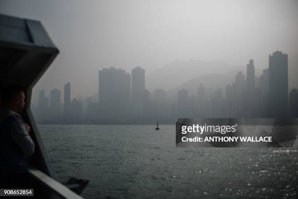 Passenger stands on the upper deck of a commuter ferry as smog engulfs residential and commercial buildings in Hong Kong on January 22, 2018. Hong...