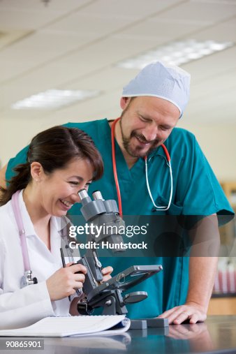 Female lab technician analyzing a sample through a microscope Female lab technician analyzing a sample through a microscope