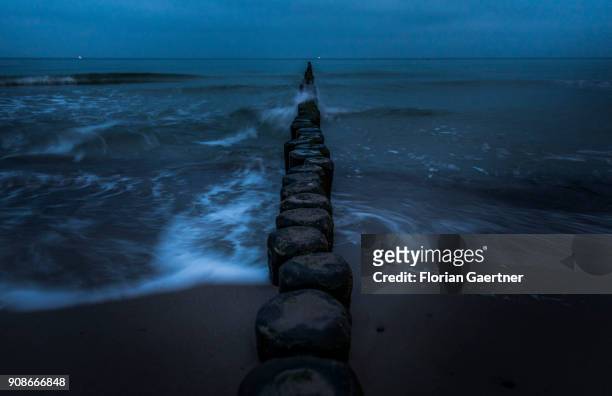 The beach and groynes of the baltic sea are pictured during blue hour on January 20, 2018 in Warnemuende, Germany.