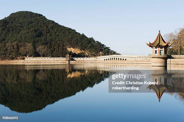 an ancient bridge reflected in the waters of a reservoir at lushan mountain, unesco world heritage site, jiangxi province, china, asia - lushan china stock-fotos und bilder