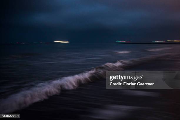 The beach and waves of the baltic sea are pictured during blue hour on January 20, 2018 in Warnemuende, Germany.