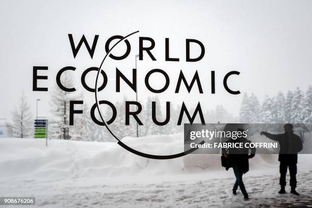 Security guard show the way to a man outside of the Davos Congress Centre under snow ahead of the opening of the World Economic Forum 2018 annual...