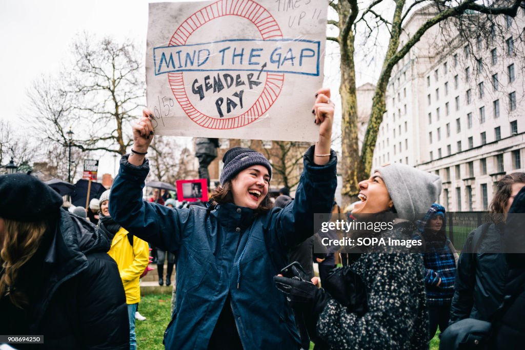 Two women seen laughing while holding a placard during the...