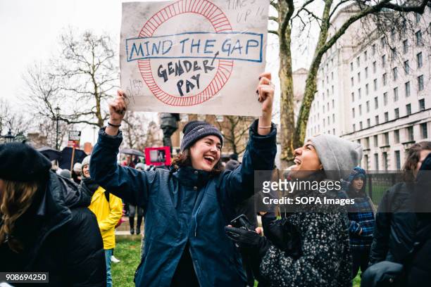 Two women seen laughing while holding a placard during the march. Scores of women across the United Kingdom took to the streets on Sunday to protest...