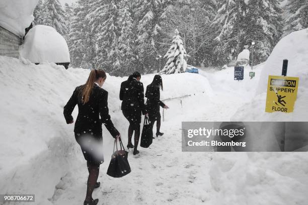 Workers walk down a snow covered path beside the Congress Center during heavy snowfall ahead of the World Economic Forum in Davos, Switzerland, on...