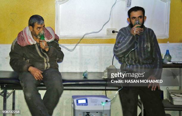 Syrian men wear oxygen masks at a make-shift hospital following a reported gas attack on the rebel-held besieged town of Douma in the eastern Ghouta...