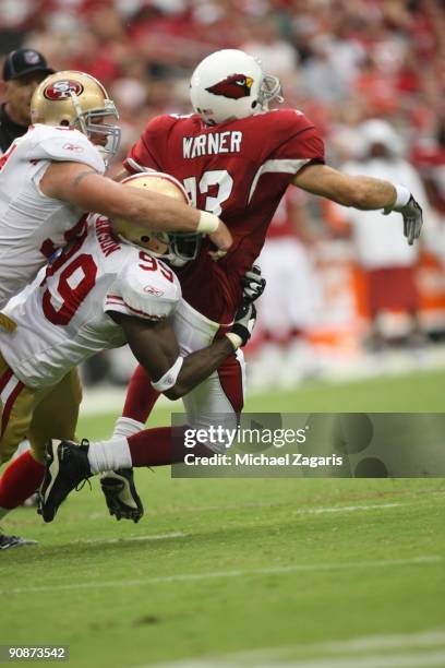 Kurt Warner of the Arizona Cardinals throws an interception while being pressured by Manny Lawson and Justin Smith of the San Francisco 49ers during...