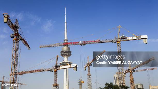 Picture taken on January 22, 2018 shows tower cranes operating at a construction site in Kuwait City with the 372-metre-high Liberation Tower seen in...