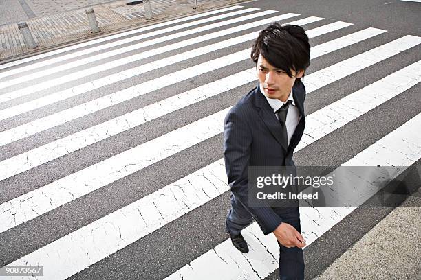 businessman crossing road, looking away - pedestrian crossing man stock pictures, royalty-free photos & images