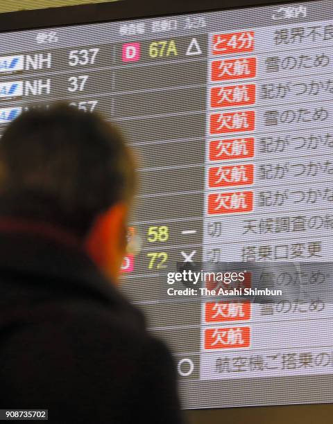 Man watches a screen displaying flight cancellation at Haneda Airport on January 22, 2018 in Tokyo, Japan. The Japan Meteorological Agency is...