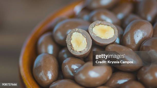 chocolate-coated almonds in glass bowl - almond stock pictures, royalty-free photos & images