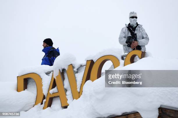 An armed member of the Swiss Police watches from the roof of the Hotel Davos ahead of the World Economic Forum in Davos, Switzerland, on Monday, Jan....