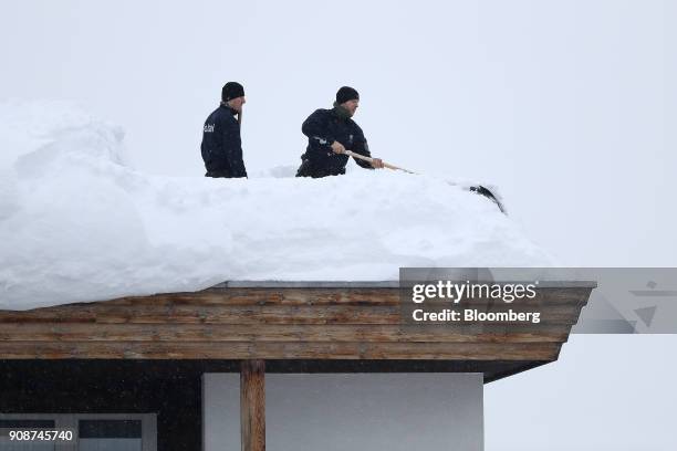 Members of the Swiss Police use shovels to clear a position on the roof of the Hotel Davos ahead of the World Economic Forum in Davos, Switzerland,...