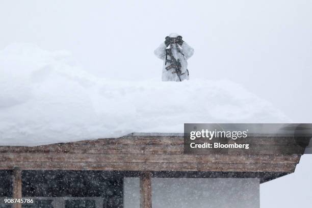An armed member of the Swiss Police uses binoculars from the roof of the Hotel Davos ahead of the World Economic Forum in Davos, Switzerland, on...