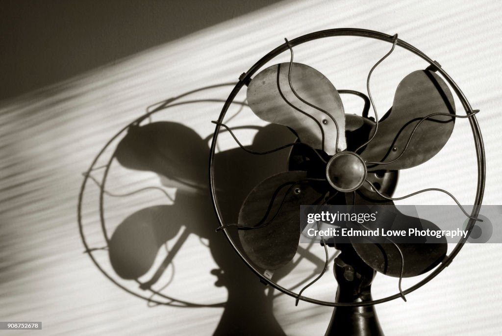 Antique Fan With Light Streaming Through the Window Blinds.