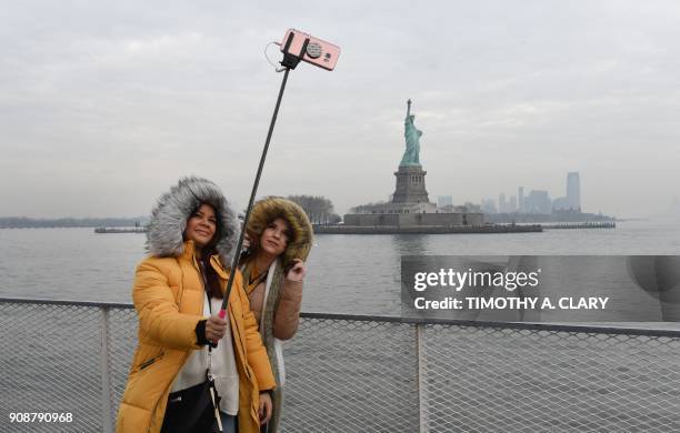 Tourist Jorden Lyle and Tory Plunkett from England take pictures aboard the Miss Ellis Island Ferry Boat as the first visitors arrive Monday morning...