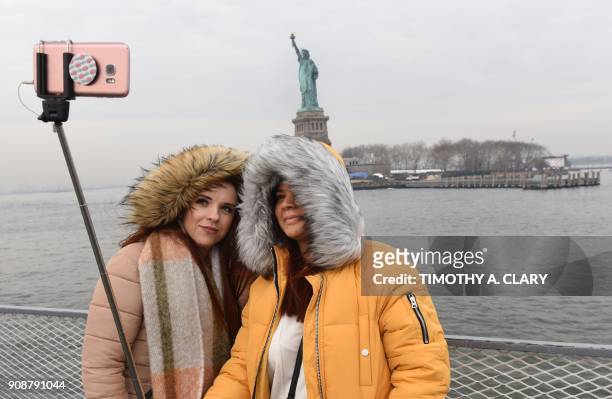 Tourist Jorden Lyle and Tory Plunkett from England take pictures aboard the Miss Ellis Island Ferry Boat as the first visitors arrive Monday morning...
