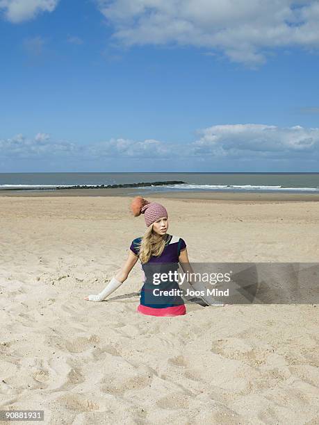 young woman sticking in the sand on beach - buried in sand stock-fotos und bilder