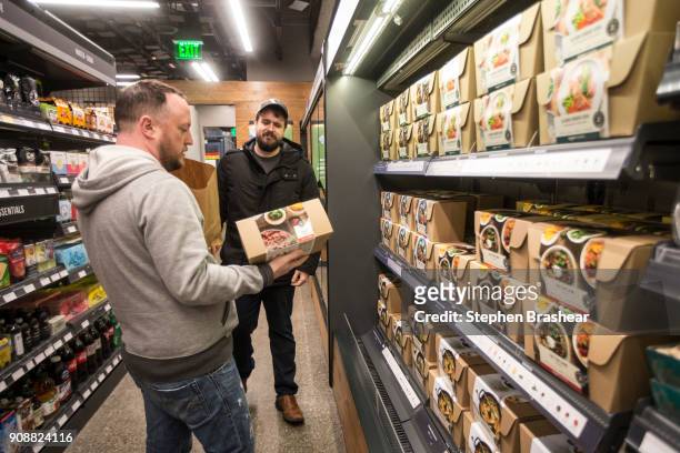 Shoppers Peter Freese, right, and Peter Ray check out pre-made meals at the Amazon Go January 22, 2018 in Seattle, Washington. After more than a year...