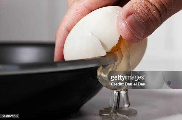 man cracking egg on side of bowl - cracked egg stock-fotos und bilder