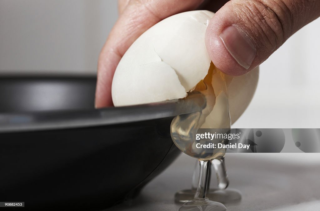Man cracking egg on side of bowl