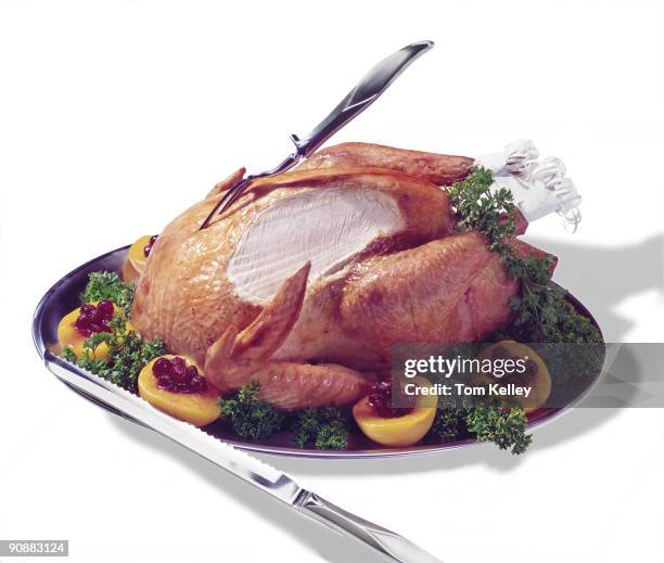 View of a cooked, partially carved turkey on platter garnished with fruit, as seen against a white background, January 1985.