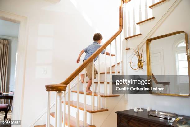 young boy running upstairs in upscale home - child running up stairs stock pictures, royalty-free photos & images