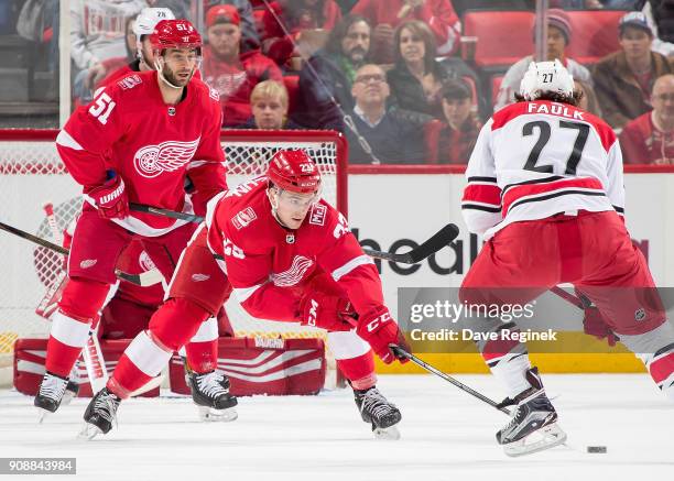 Dominic Turgeon and Frans Nielsen of the Detroit Red Wings defend in front of the net from Justin Faulk of the Carolina Hurricanes during an NHL game...