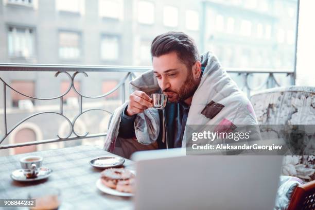 drinking his first morning coffee in front of laptop on balcony - friends donut stock pictures, royalty-free photos & images