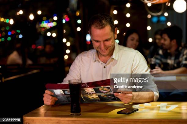 uomo felice che mangia in un ristorante e legge il menu - man eating at diner counter foto e immagini stock
