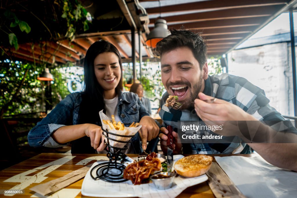 Loving couple eating together at a burgerâs restaurant